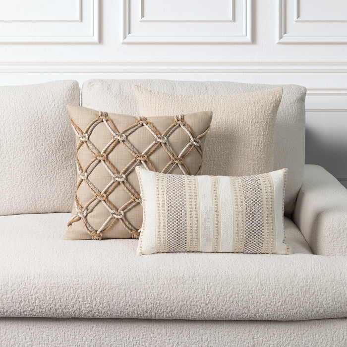 Two decorative throw pillows on a textured cream boucle sofa against a white paneled wall. One pillow is beige with a rope lattice pattern, and the other is cream and beige with vertical woven stripes.
