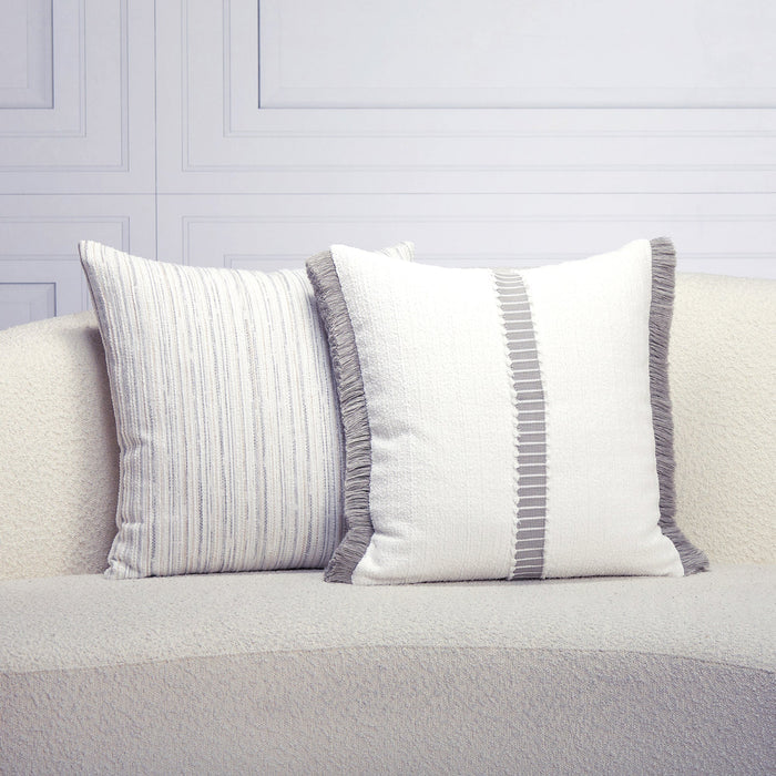 Two decorative pillows with striped patterns on a light gray sofa against a light gray wall.