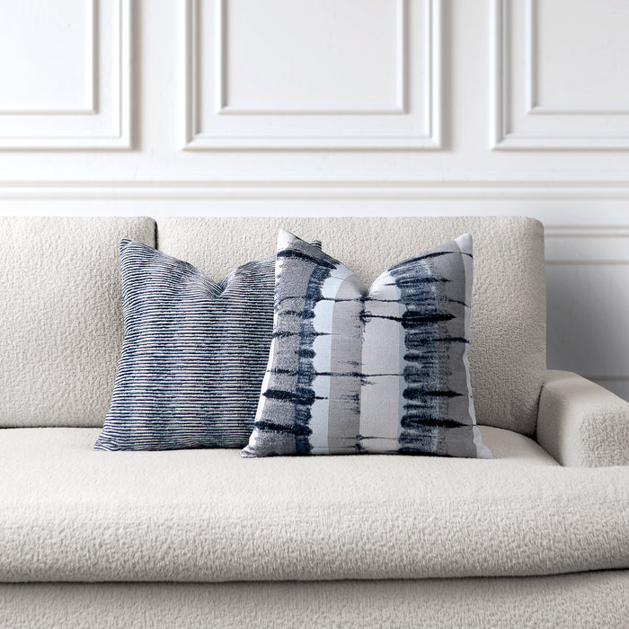 Decorative pillows with abstract patterns on a beige sofa against a white paneled wall.