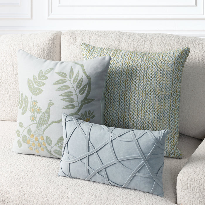 Three decorative throw pillows arranged on a cream boucle sofa. The front pillow is light blue with a raised crisscross lattice pattern.