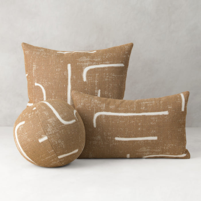 Three brown pillows with white abstract patterns on a gray background