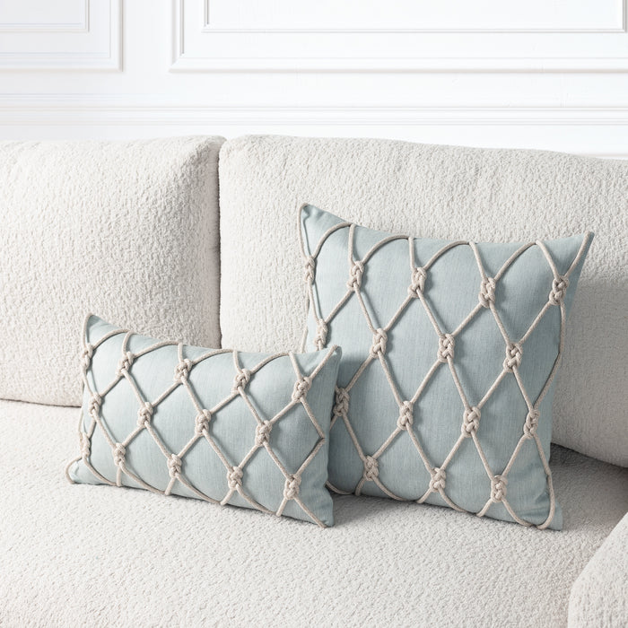 Two square decorative throw pillows in a pale blue-gray fabric with a beige rope knotted lattice pattern, styled on a textured cream boucle sofa.