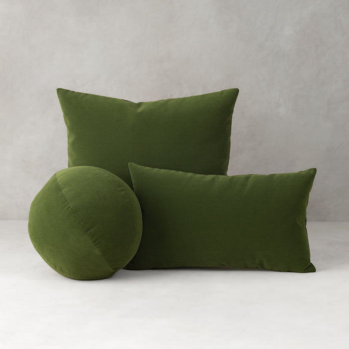 Three green pillows on a white surface with a gray background