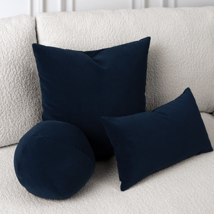 Navy blue round and rectangular cushions on a light gray sofa.
