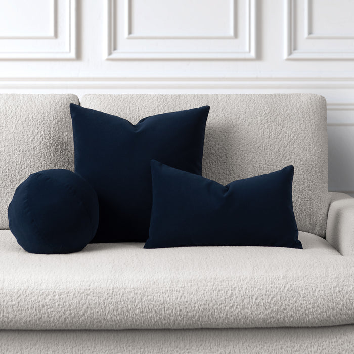 Navy blue cushions on a light gray sofa against a white paneled wall.