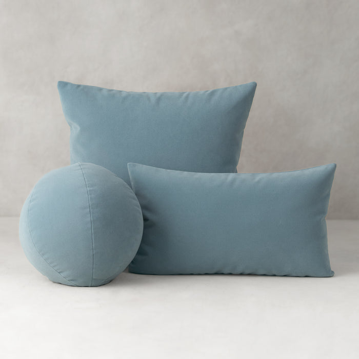 Three blue pillows of different shapes on a light gray background