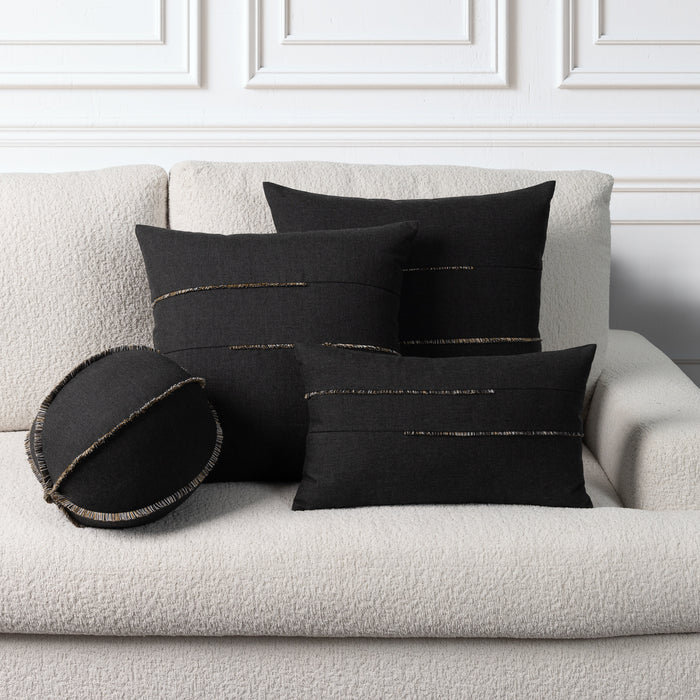 Four black decorative throw pillows with metallic gold stitched details arranged on a textured off-white boucle sofa against a white paneled wall.