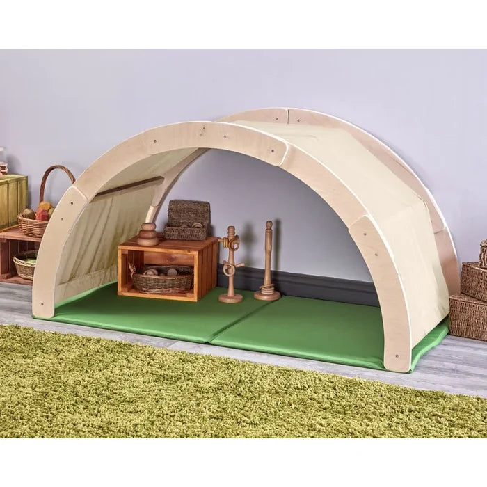 Wooden playhouse with green mat on a gray floor
