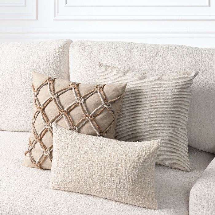 Three decorative throw pillows in neutral beige and cream tones arranged on a textured cream sofa. One pillow features a rope-style lattice pattern, one has subtle horizontal ribbing, and one is smooth and textured.