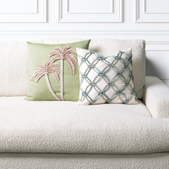 Two decorative pillows on a beige sofa with a white paneled wall background.