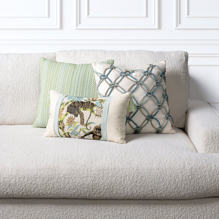 Decorative outdoor safe pillows on a beige sofa against a white paneled wall.