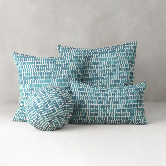 Set of four blue patterned pillows on a white surface with a gray background