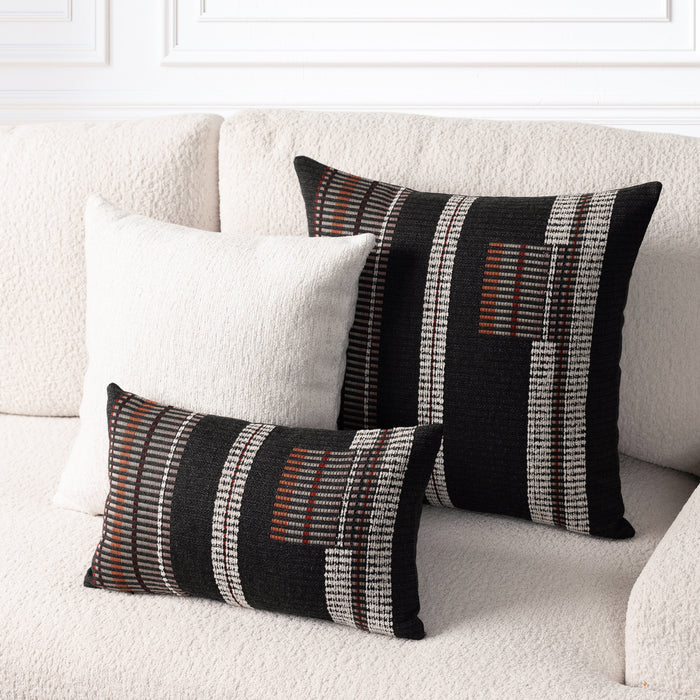 Two decorative throw pillows on a textured cream boucle sofa. One tall square pillow and one matching horizontal lumbar pillow, both featuring a black base with vertical white textured stripes and rust-orange geometric accents.